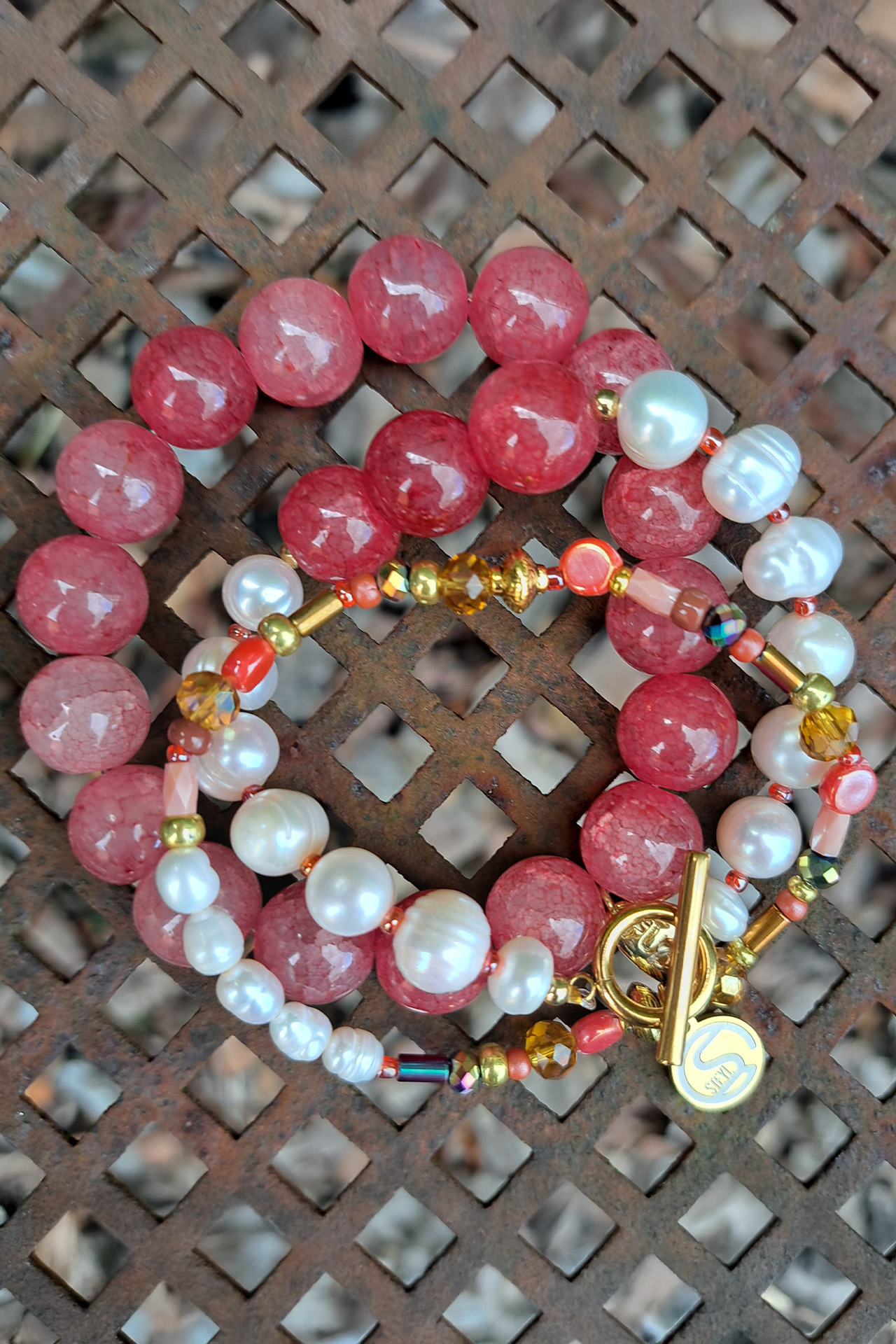 Armband met zoetwaterparels en glaskralen Steyl-Sieraden Handgemaakte sieraden Horst – vrouw draagt roze kralenketting en zilveren kettingen met smileys, sterretjes en klavertje vier van Steyl Sieraden