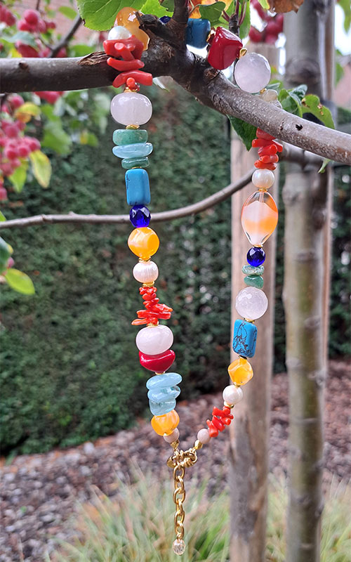 260429-Home-1 Handgemaakte sieraden Horst – vrouw draagt kleurrijke kralenketting met schelp en armband van Steyl Sieraden